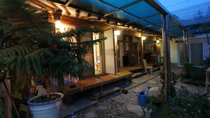 A traditional Japanese house with a wooden porch, a tatami mat room, and a garden area with potted plants and a stone path. - 1928 Suimmaru Hanok Guesthouse (Jeonju)