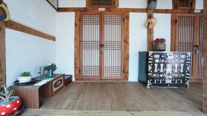 A traditional Japanese room with wooden sliding doors, a sewing machine, and a cabinet with decorative tiles. - 1928 Suimmaru Hanok Guesthouse (Jeonju)