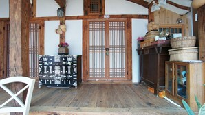 A traditional Japanese room with tatami flooring, a shoji screen door, and a wooden cabinet with baskets. - 1928 Suimmaru Hanok Guesthouse (Jeonju)