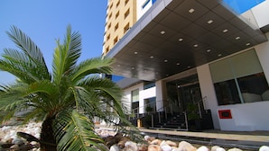 Un edificio moderno con tejado plano, amplias ventanas y una palmera en primer plano.