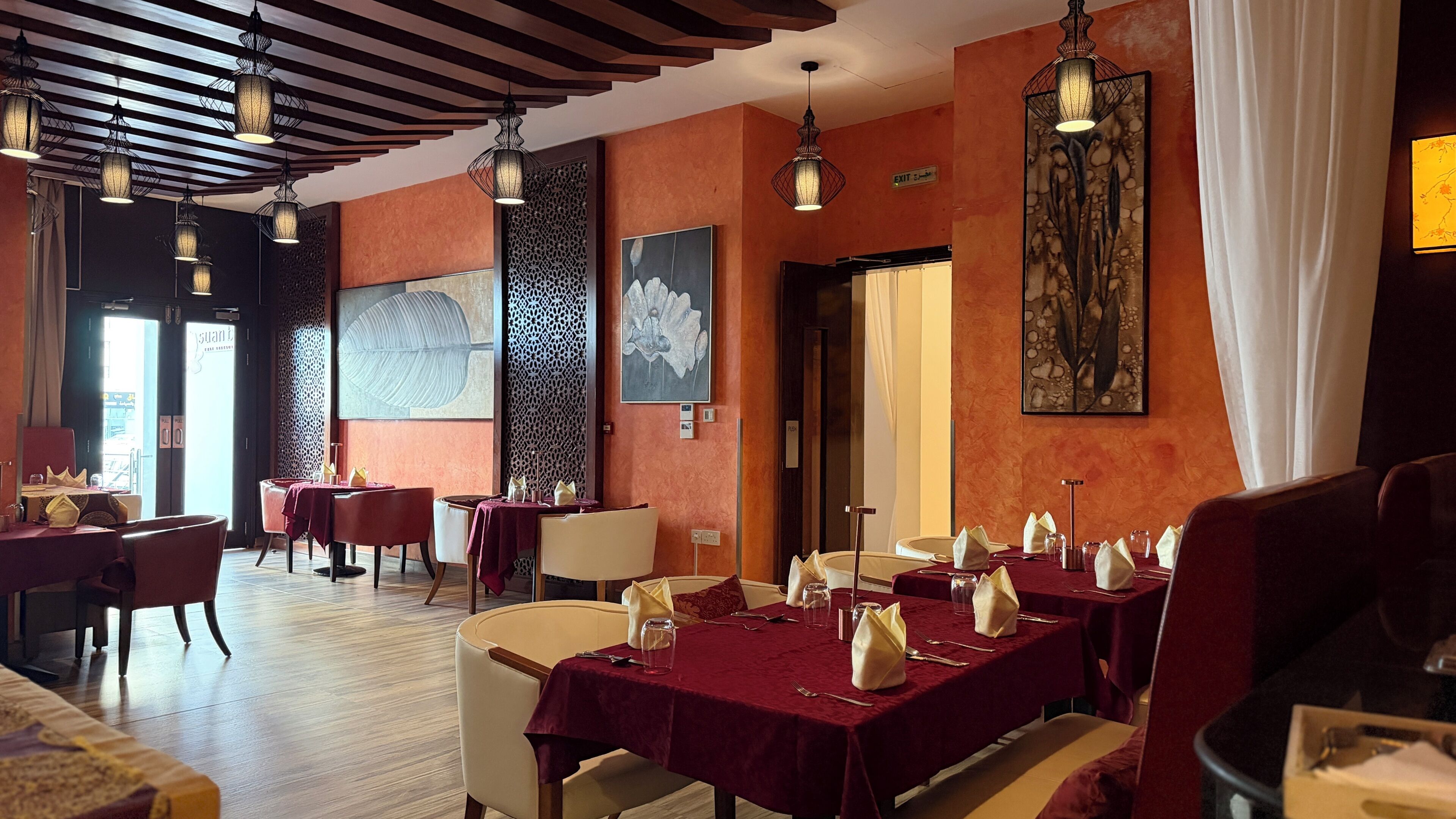 Ein Restaurant mit gedeckten Tischen, Holzbalkendecke und Kunstwerken an den Wänden.