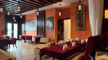 Ein Restaurant mit gedeckten Tischen, Holzbalkendecke und Kunstwerken an den Wänden.