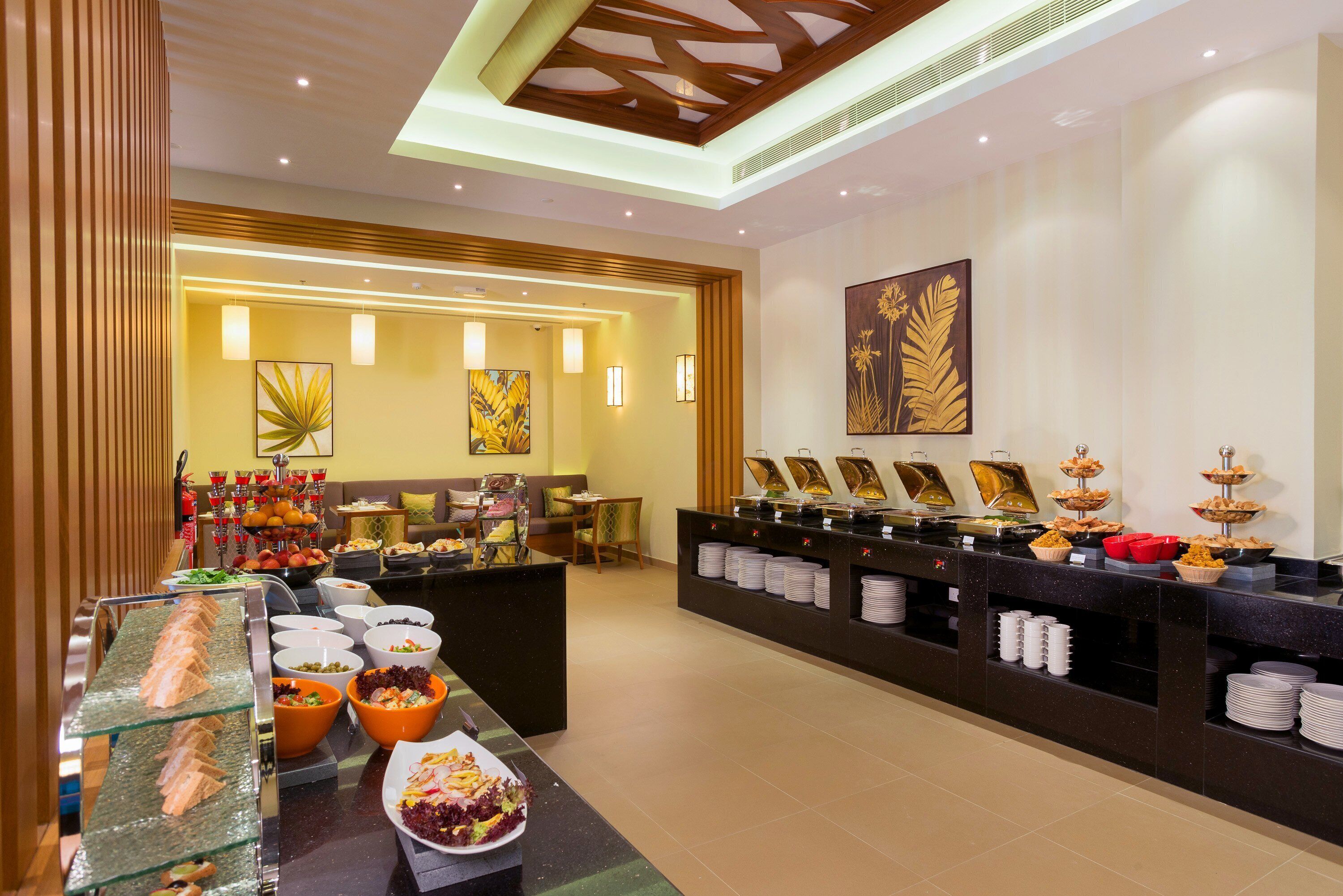A buffet area with various food options, a seating area, and artwork on the walls.