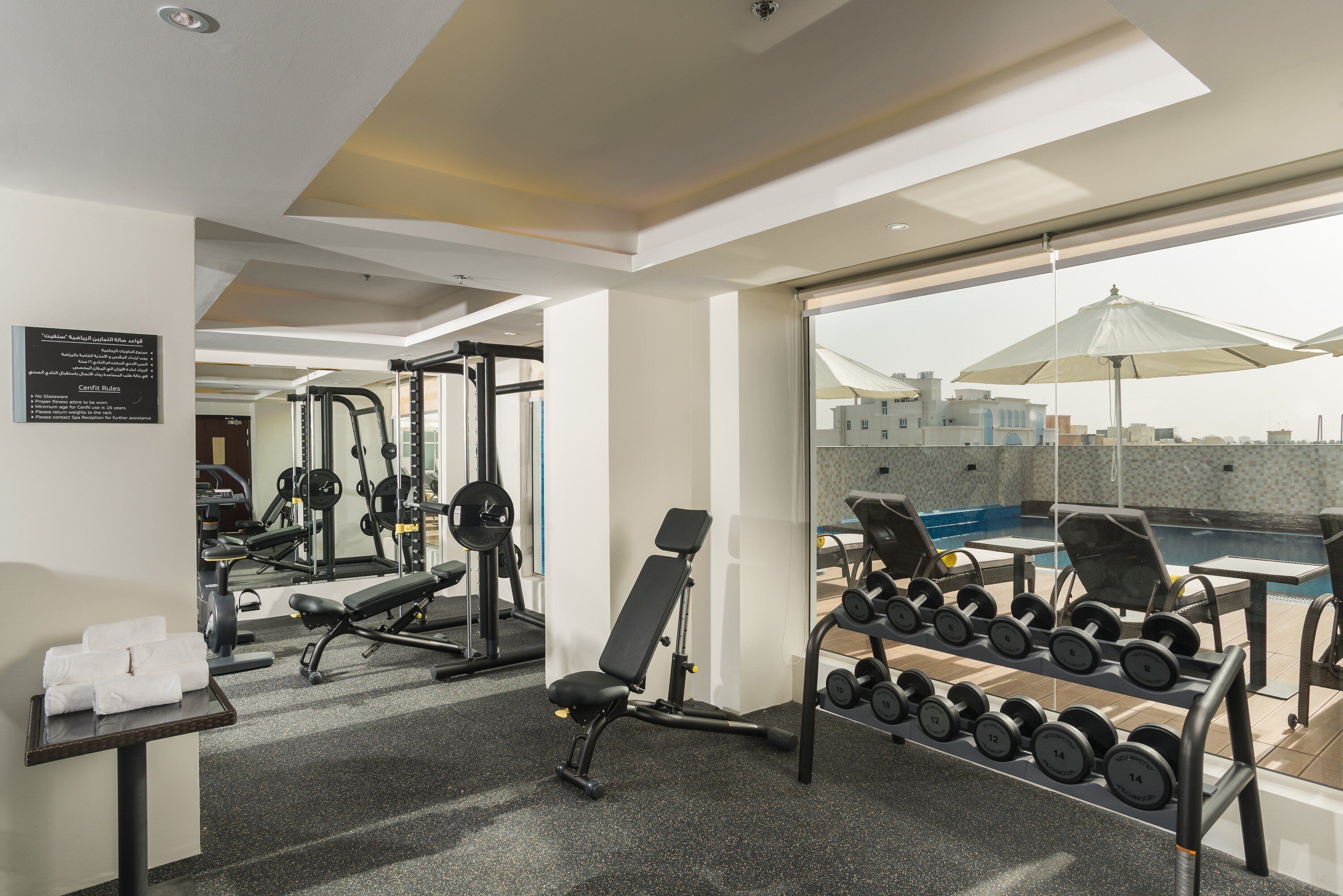A gym with exercise equipment, a bench, and a rack of dumbbells.