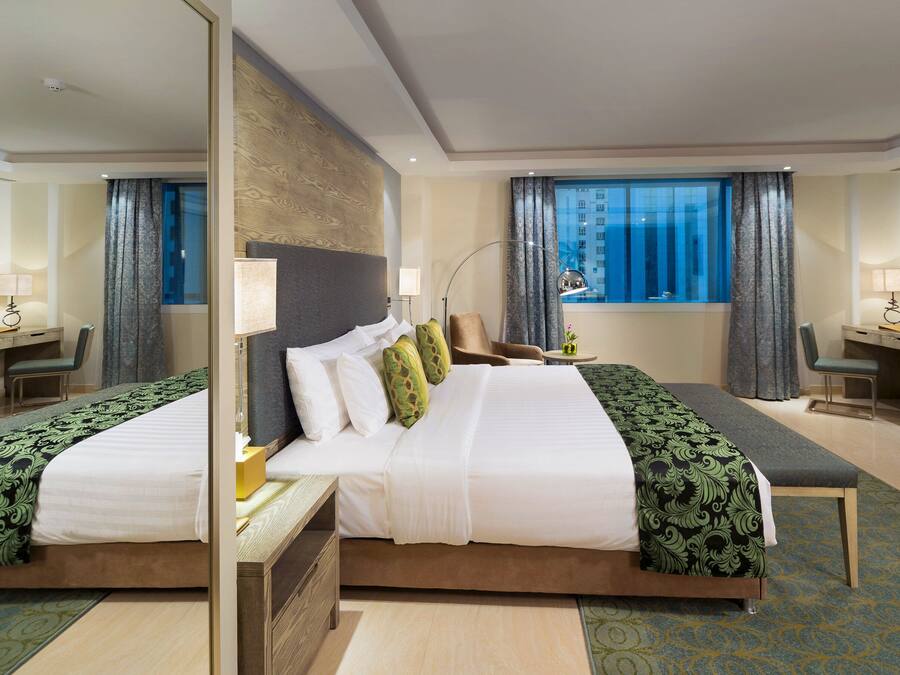 Una habitación de hotel con una cama grande, un escritorio, una silla y una ventana con cortinas.