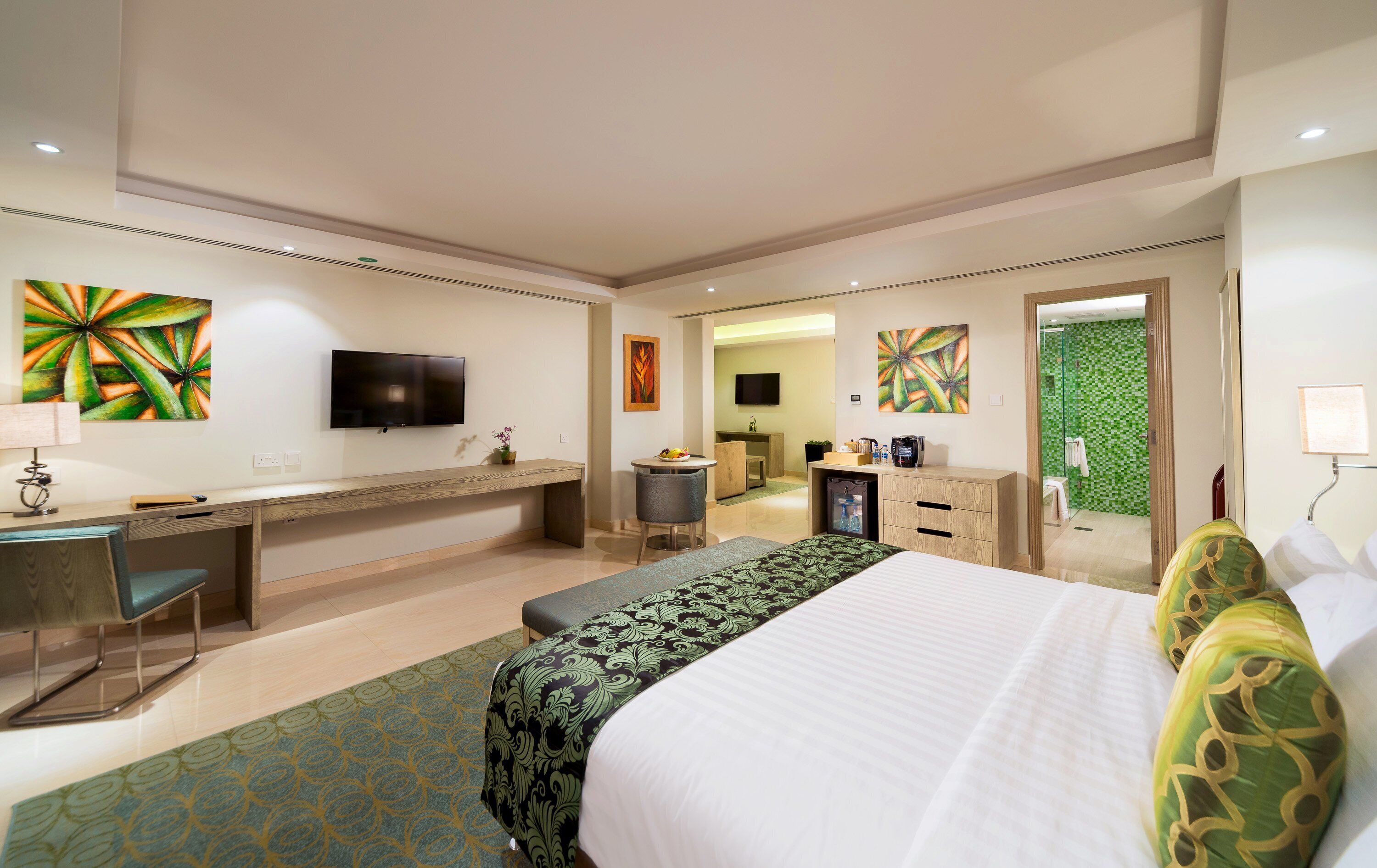 A hotel room with a bed, desk, chair, TV, and bathroom.