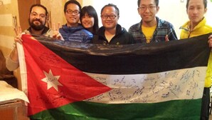 A group of people holding a flag with signatures. - Jordan River Hotel (Amman)