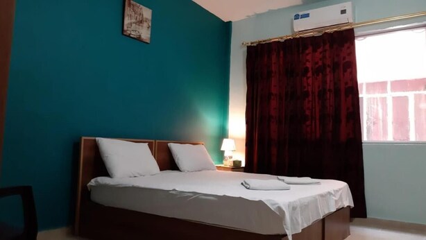 A neatly made bed with white linens, a wooden headboard, and a bedside lamp. - Jordan River Hotel (Amman)
