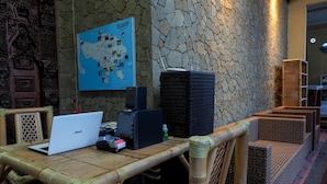 A room with a bamboo table, a laptop, a speaker, and a map on the wall. - Lagas Hostel (Ubud)