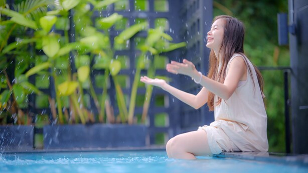 A person sitting by a pool with water splashing around them. - 9.5 Hotel (Chiang Mai)