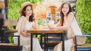 Two people seated at a table with a hanging light fixture above, surrounded by greenery and a wooden slatted wall. - 9.5 Hotel (Chiang Mai)
