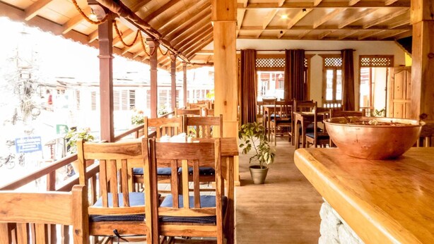 A wooden interior with tables and chairs, a large bowl on the counter, and a potted plant. - Tristar Hotel (Pokhara)