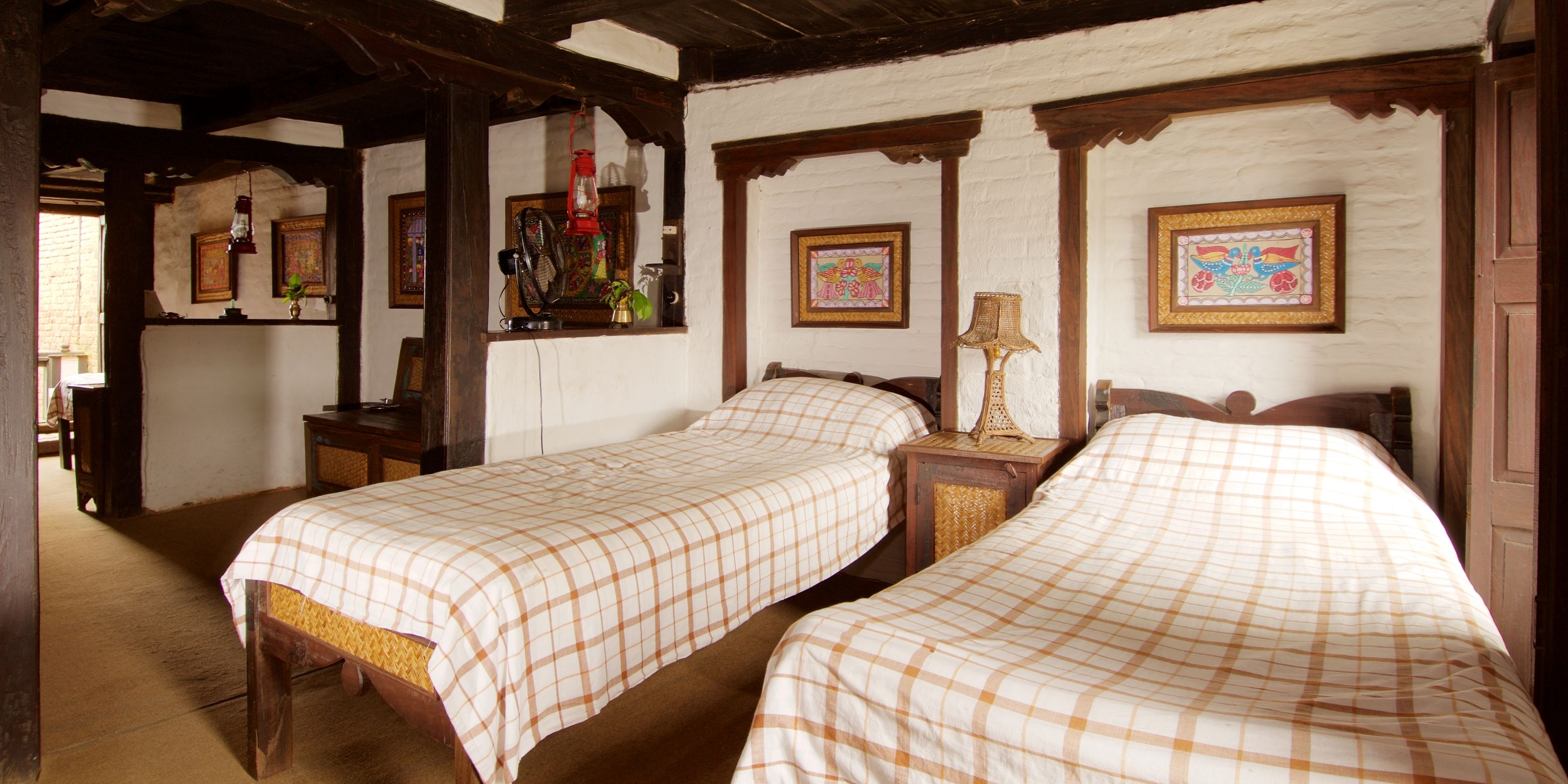 Una habitación tradicional con dos camas individuales, vigas de madera y un estilo rústico.