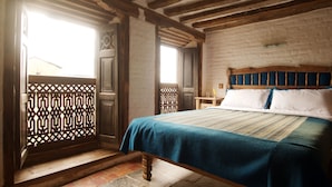 A traditional bedroom with a wooden bed, a patterned window, and a wooden floor. - The Old Inn (Bandipur)