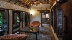 A rustic interior with exposed wooden beams, a stone floor, and traditional furnishings. - The Old Inn (Bandipur)