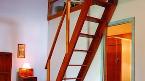 A wooden staircase leading to an upper level, a wooden bench, and a door to a bathroom. - Agriturismo Cascina degli Ulivi (Novi Ligure)