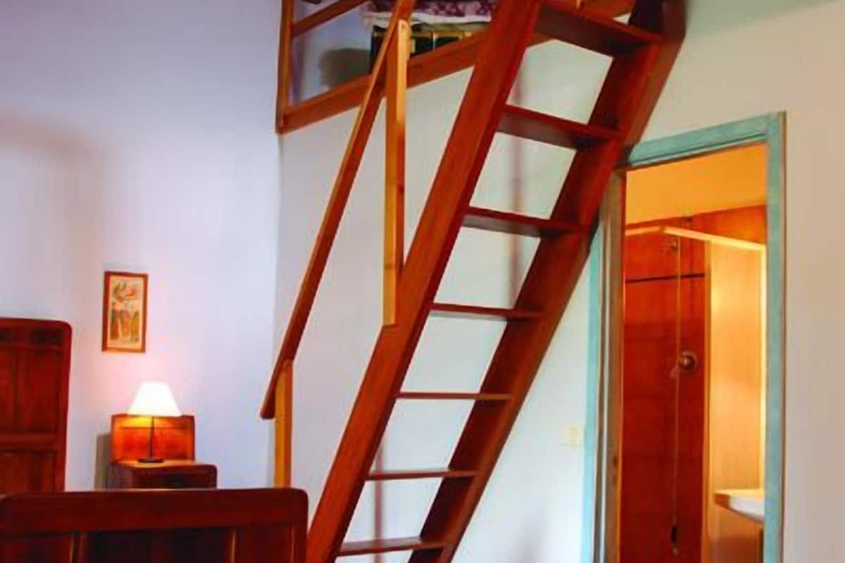 A wooden staircase leading to an upper level, a wooden bench, and a door to a bathroom.