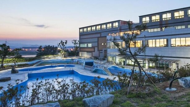 Ein modernes Hotel mit Poolbereich, großen Fenstern und Meerblick.