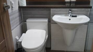 Un baño pequeño con inodoro, lavamanos y un cubo de basura.