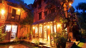 Un bâtiment traditionnel doté d’un patio couvert, d’un chemin en pierre et de plantes en pot.