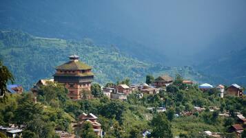 A traditional building with a circular base and a pointed roof, surrounded by houses on a hillside.