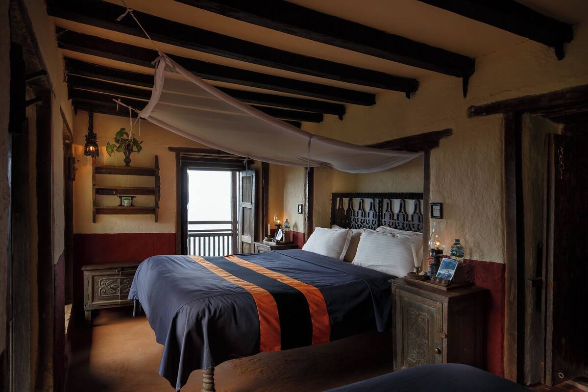 Ein traditionell eingerichteter Raum mit Bett, Nachttisch und Fenster mit Blick.