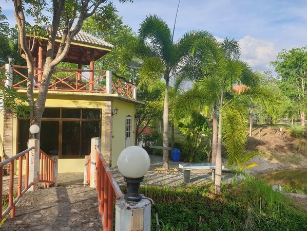 A yellow building with a covered entrance and a stone pathway leading to it.