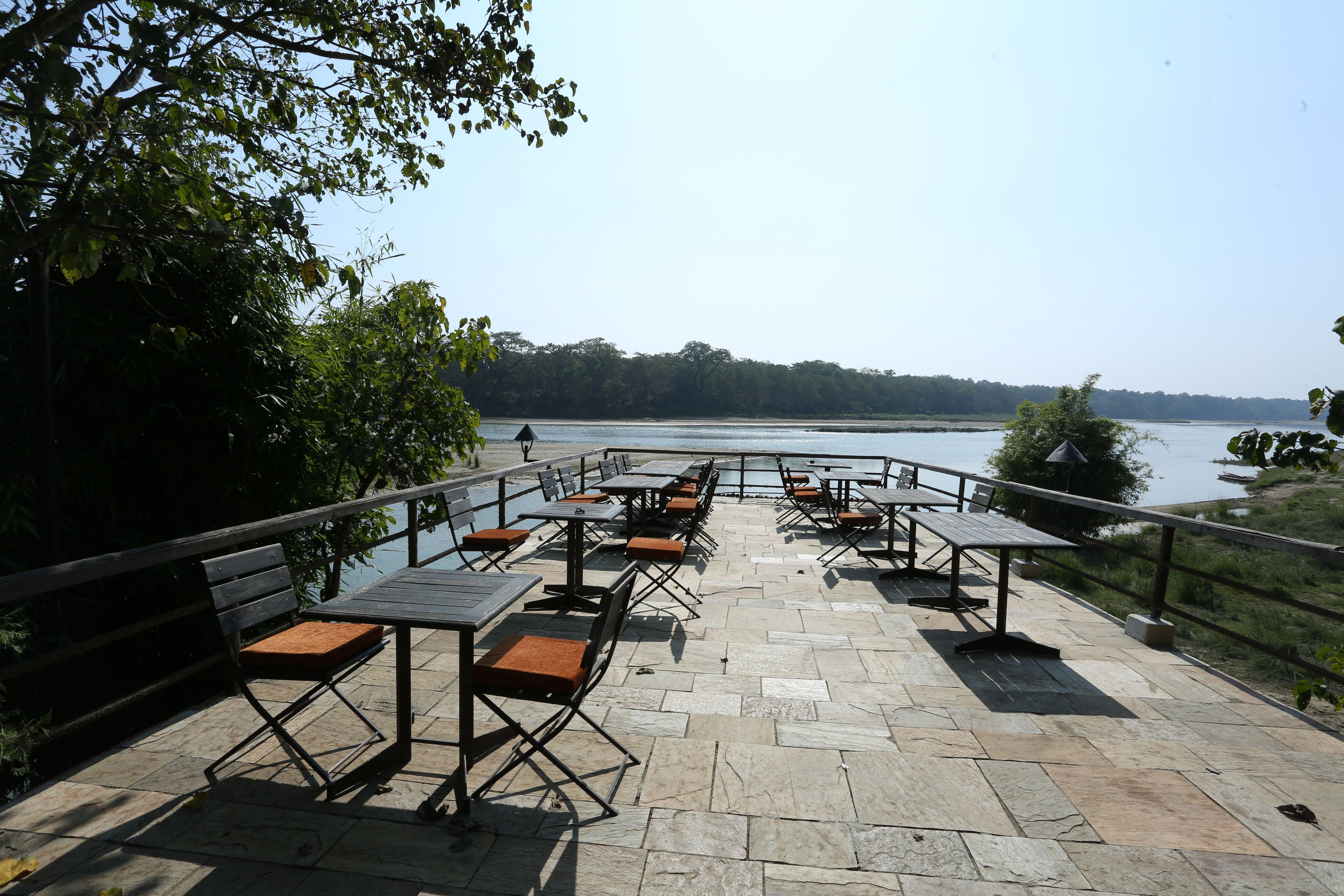 An outdoor patio with stone flooring and metal tables and benches.