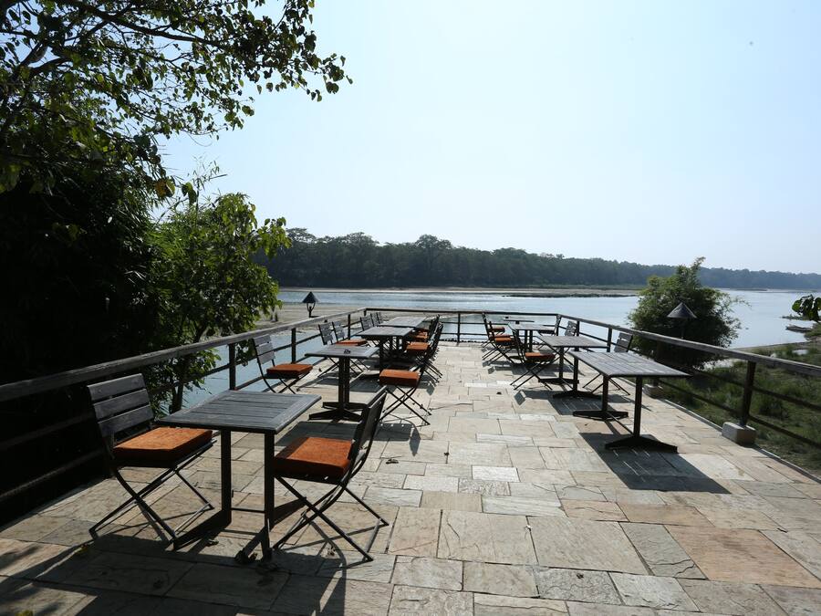 An outdoor patio with stone flooring and metal tables and benches.