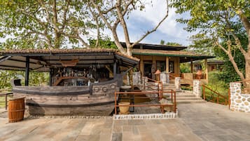 Un rústico espacio de bar con una estructura de barco de madera, escalones de piedra y una pared de piedra.
