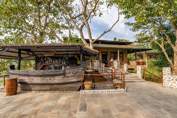 Un rústico espacio de bar con una estructura de barco de madera, escalones de piedra y una pared de piedra.