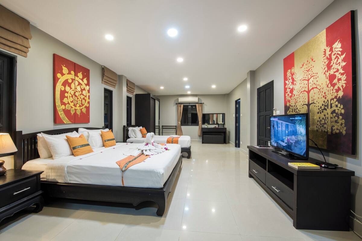 Una habitació d'hotel amb un llit gran, una televisió i obres d'art a les parets.