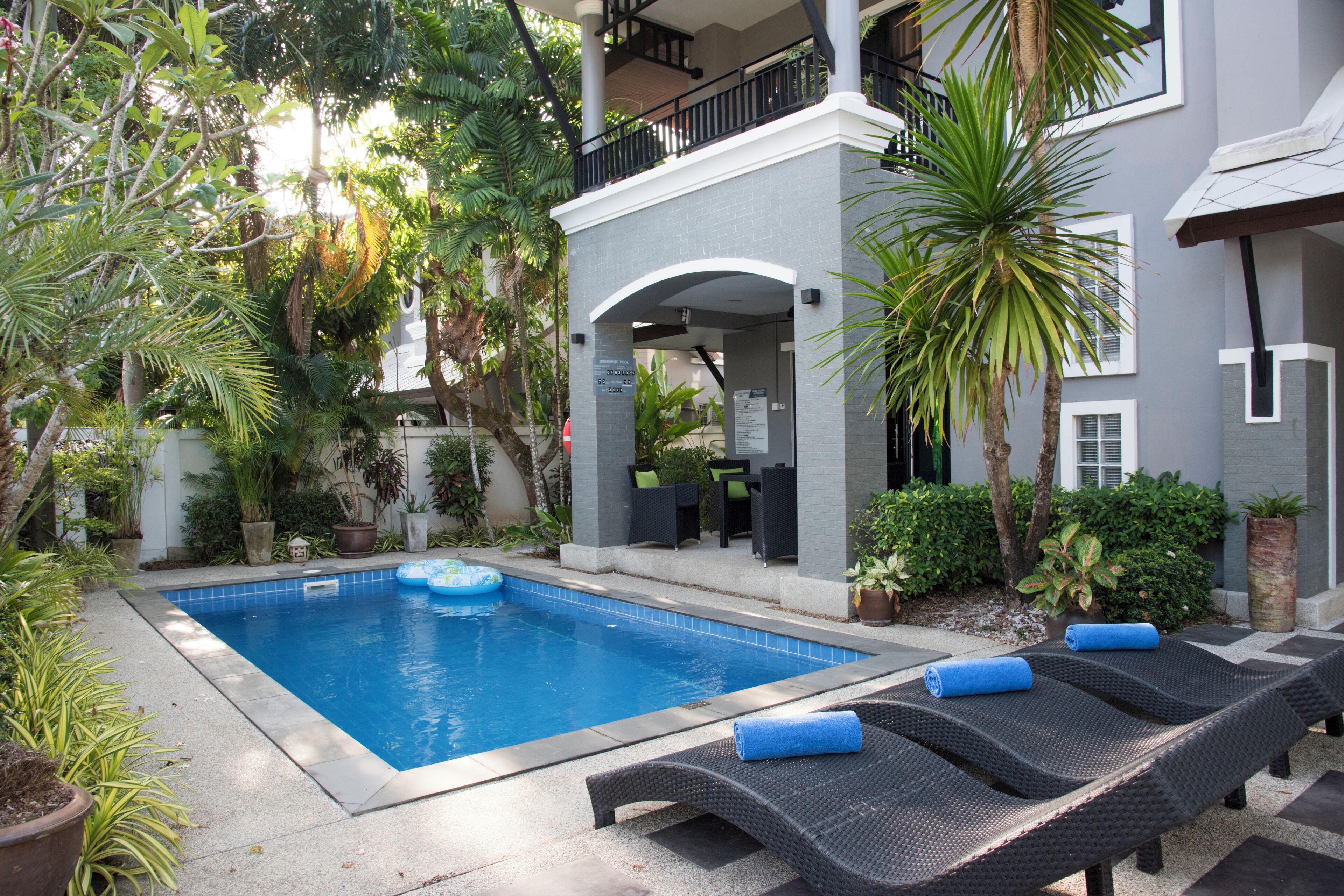 A swimming pool with lounge chairs and a covered area with a sign indicating a swimming pool.