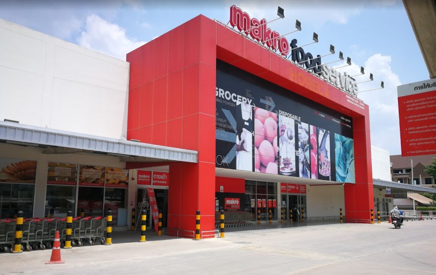 A grocery store with a prominent red facade and a large digital display advertising various products.