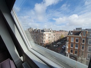 A view from a window overlooking a row of terraced houses with a clear sky. - Hotel Heye 130 (Amsterdam)