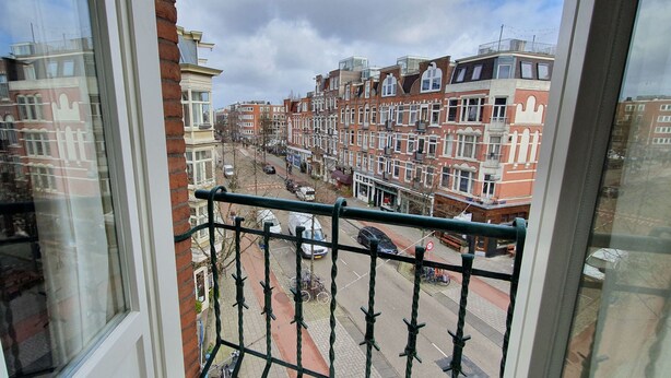 A view from a balcony overlooking a street with red brick buildings, a clear sky, and a few parked bicycles. - Hotel Heye 130 (Amsterdam)