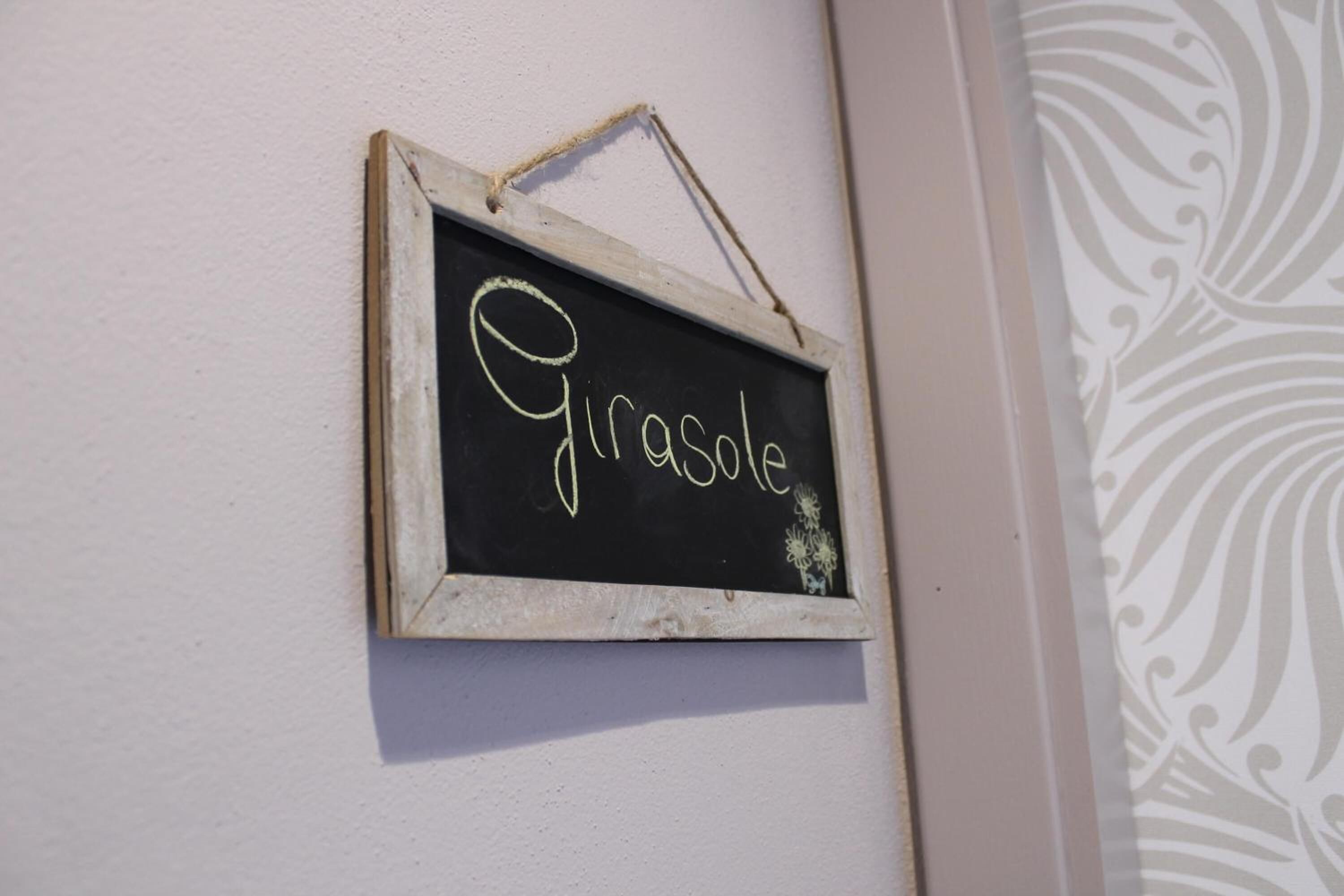 Un panneau noir, sur lequel est écrit le mot « Girasole », est accroché à un mur.