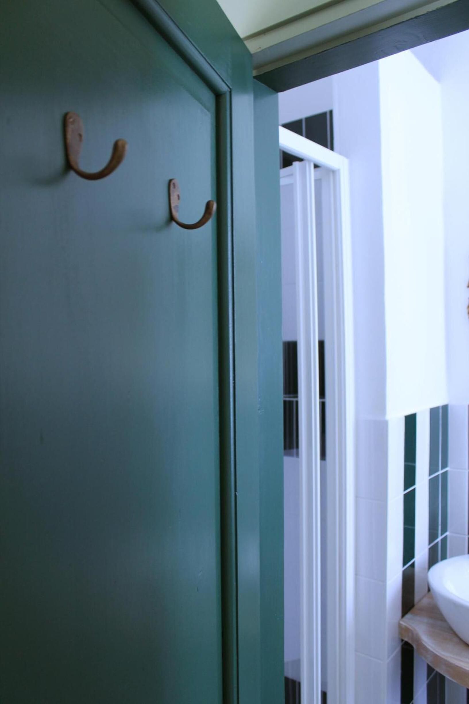 A bathroom with a green door, white sink, and green and white tiled walls.