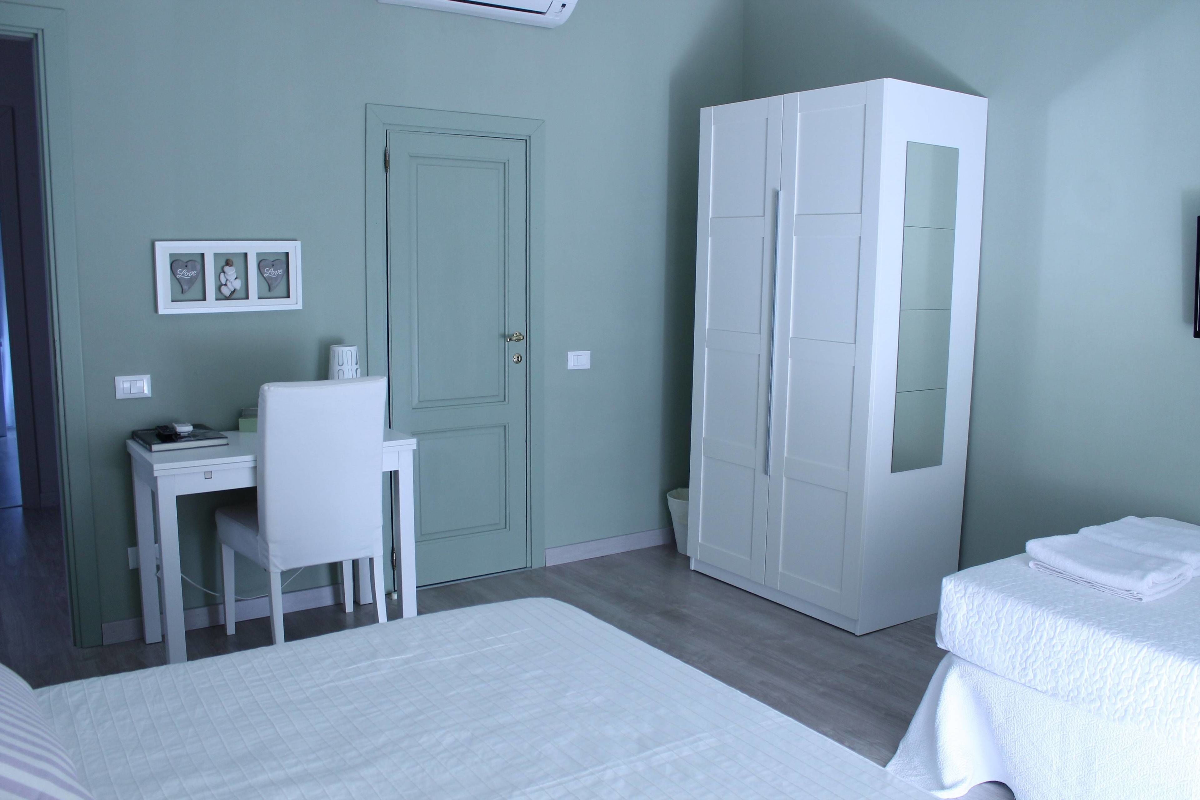 Ein Schlafzimmer mit einem Bett, einem Schreibtisch, einem Stuhl, einem Kleiderschrank und einem kleinen Tisch mit einem Handtuch.
