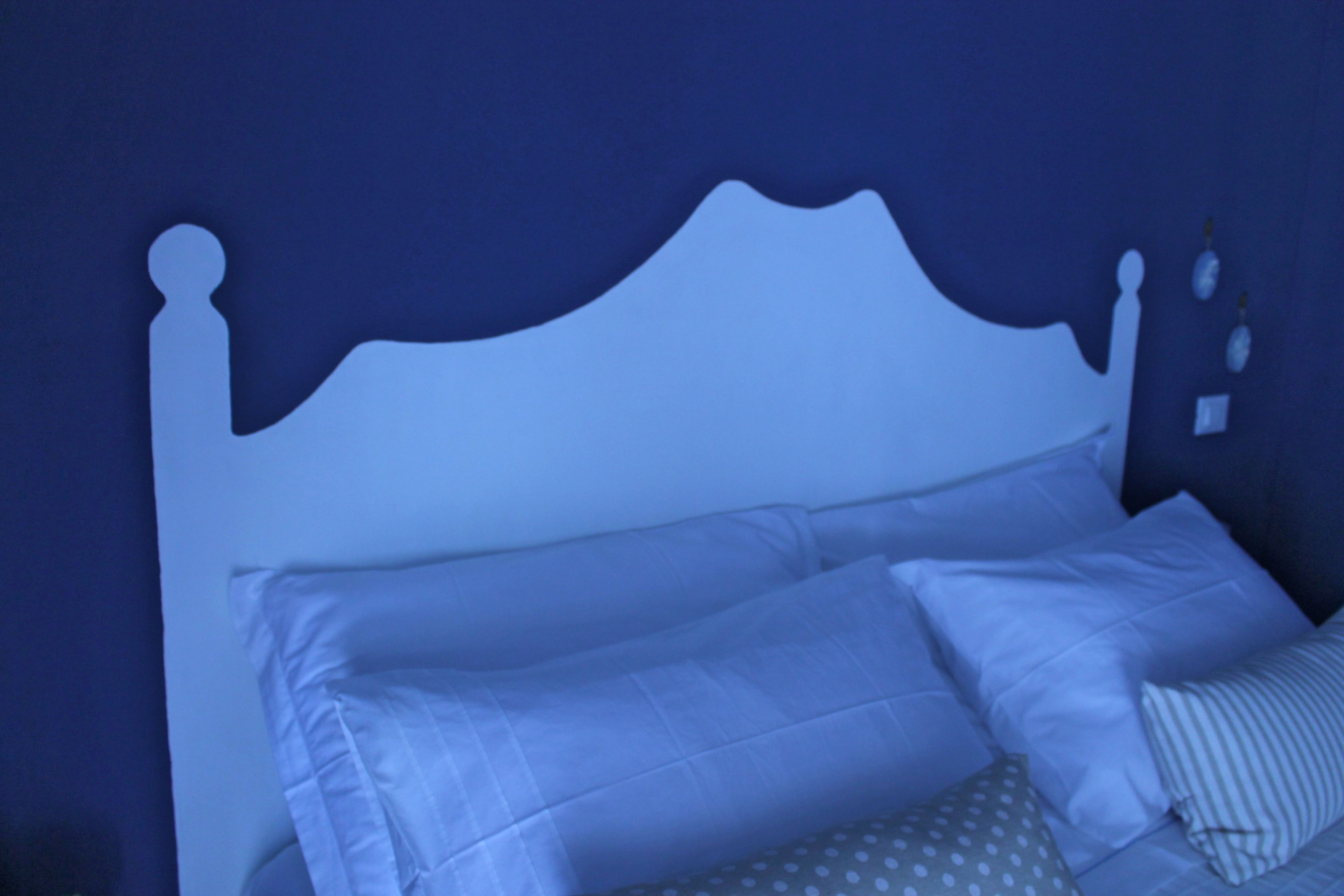 A bed with a white headboard and multiple pillows.