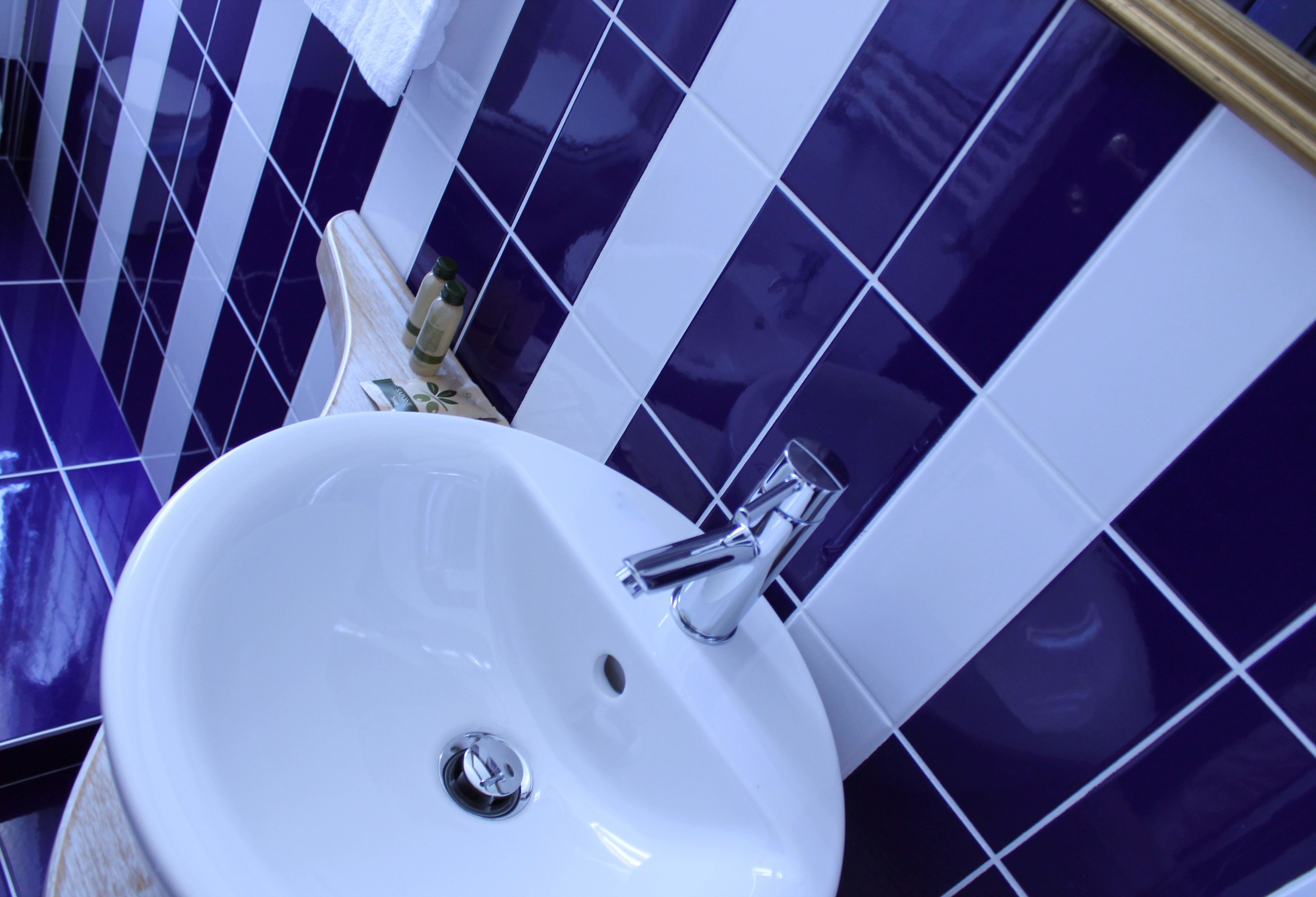 A bathroom with a white sink, chrome faucet, and blue and white tiled walls.
