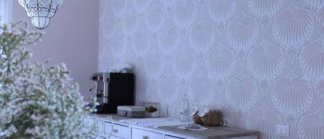 A kitchen with white cabinets, a coffee machine, and hanging plants.