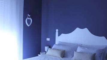 A modern bedroom with a large bed, a bedside table, and a hanging light fixture.