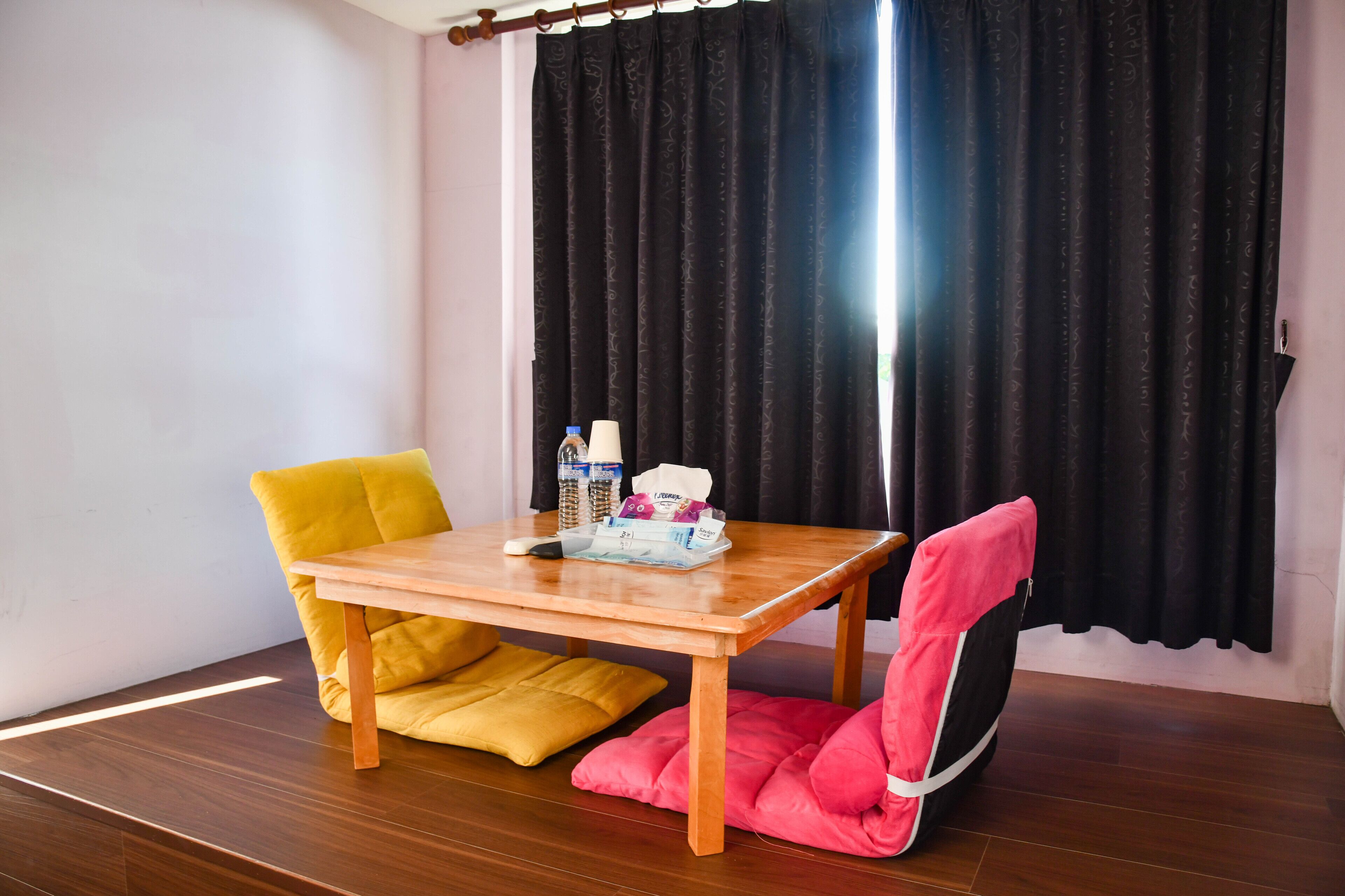 Una habitación con una mesa de madera, dos sillas, una botella y una caja de pañuelos.