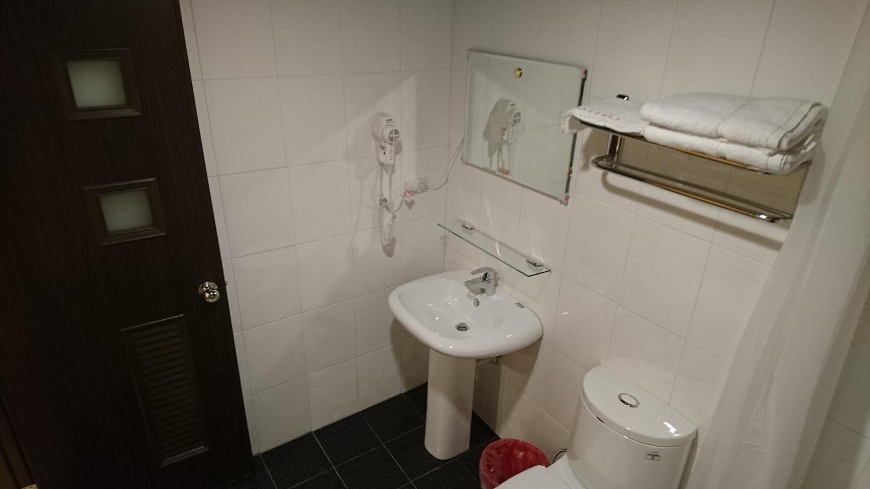 Une petite salle de bain avec un lavabo blanc, des toilettes et un porte-serviettes.