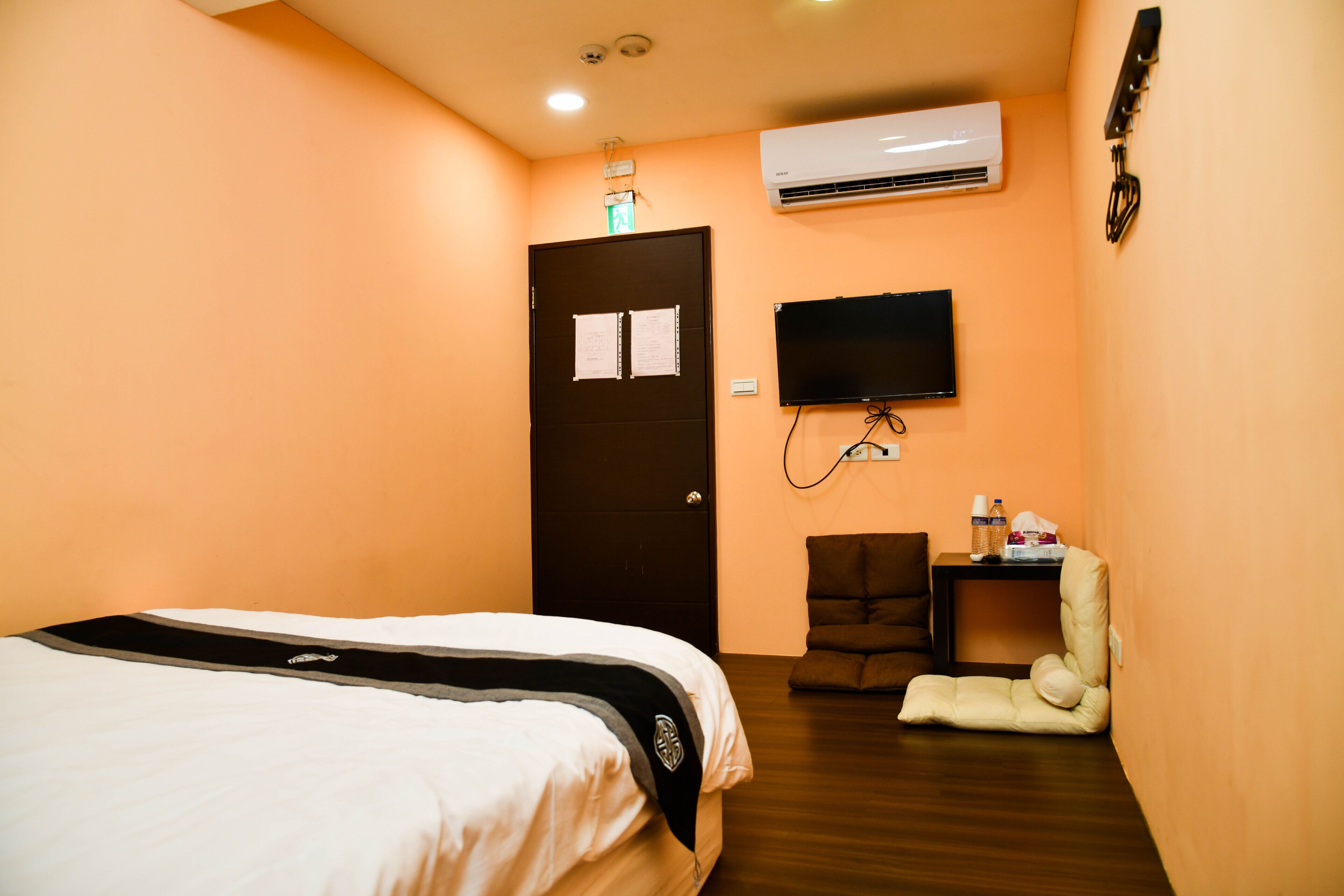 Ein Hotelzimmer mit einem Bett, einem Schreibtisch mit Stuhl, einem Fernseher und einer Klimaanlage.