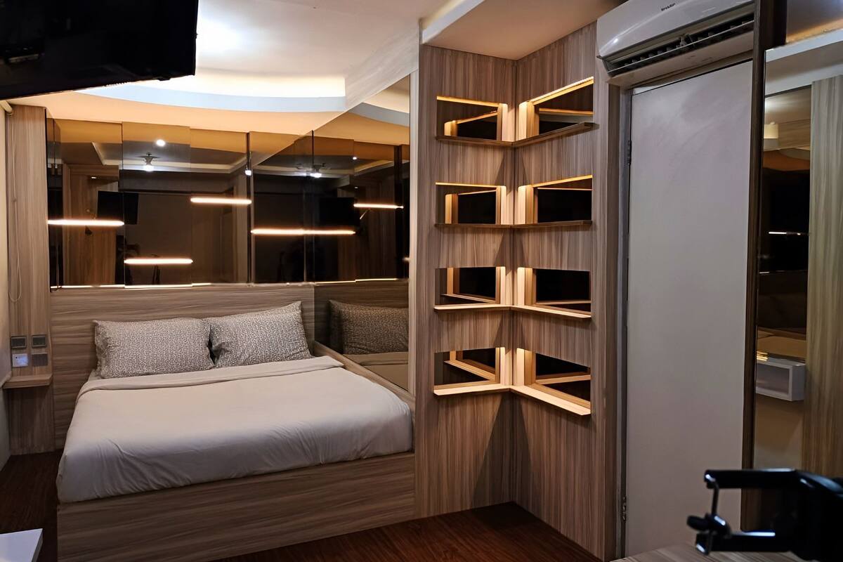 A modern bedroom with a bed, built-in shelves, and pendant lighting.