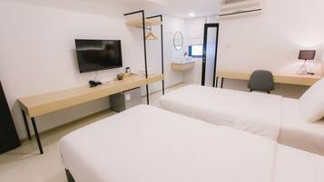 A hotel room with two beds, a desk, a TV, a mirror, and a small desk lamp.