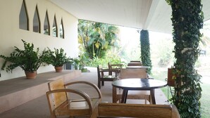 An outdoor patio with wooden furniture, potted plants, and a view of the surrounding greenery. - Royal Princess City (Lamphun)