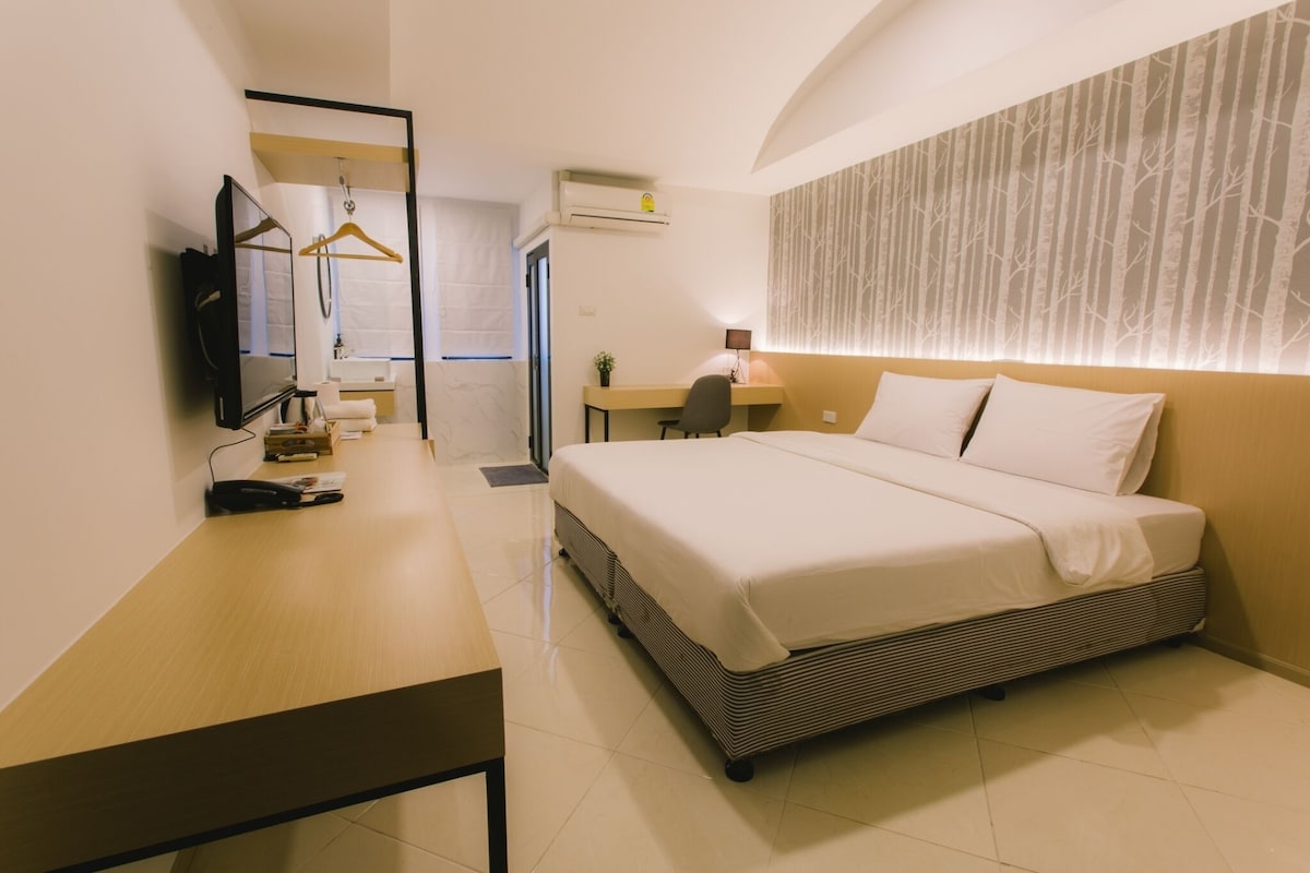 A modern hotel room with a bed, desk, and TV.